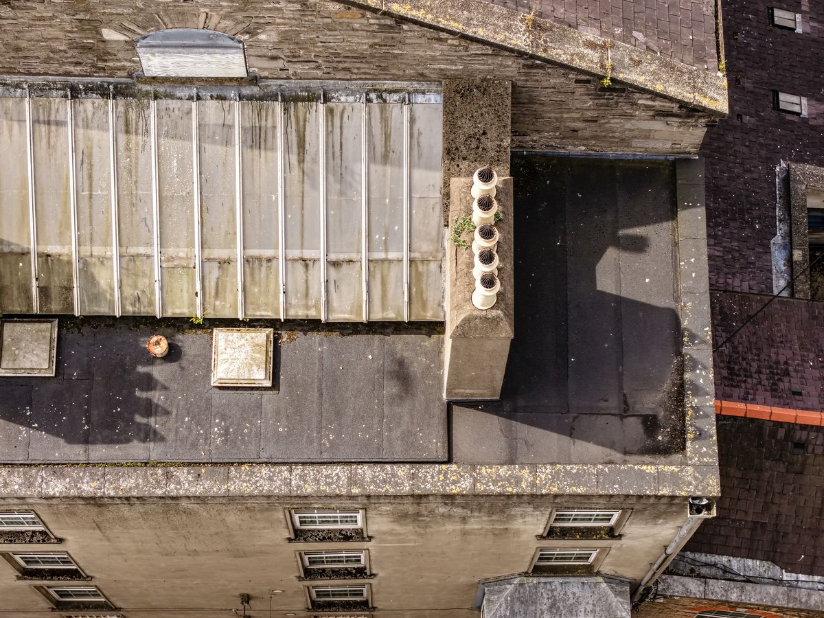 Close aerial detail of a row of chimney pots with cowls and lead flashing on a city-centre roof