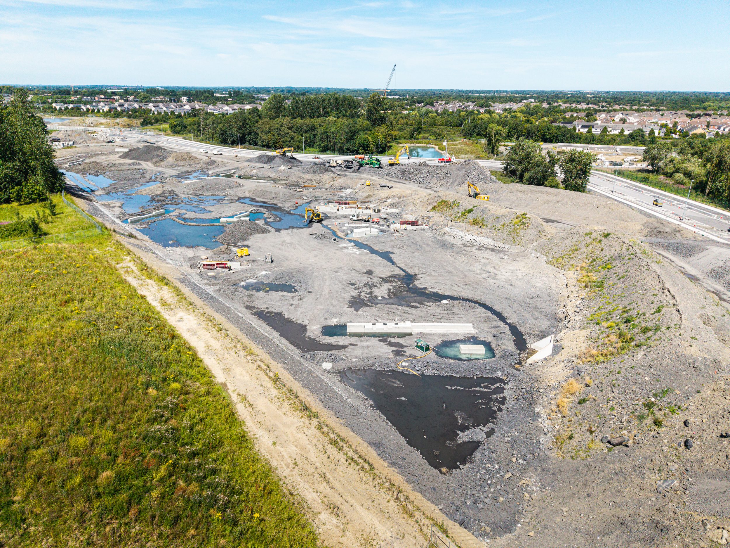Aerial view of a development site in early 2025 with bare earthworks, channels and machinery during groundworks